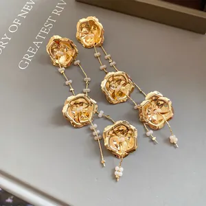 Detaillierte Nahaufnahme goldener Metallblumen-Ohrhänger mit eleganten zarten Glasperlen.