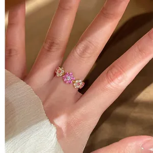 Detailopname van een 14k vergulde open ring met drie fonkelende bloemmotieven van zirkoon.