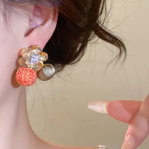 Gedetailleerde close-up van zirkonia bloemenoorbellen met kleurrijke stoffen bolletjes hangers
