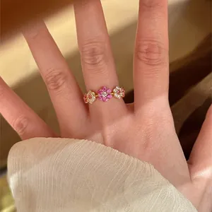 Detailweergave van een vergulde ring met drie roze en witte bloemen van zirkonia