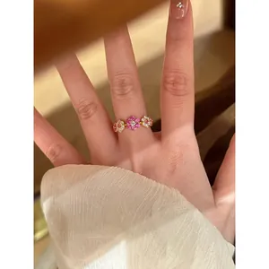 Close-up van een vergulde open ring met een sprankelend bloemmotief van zirkonia