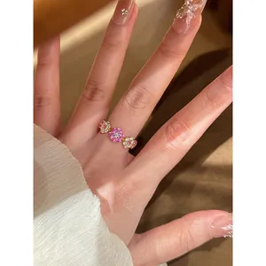 Detailweergave van een 14k vergulde ring met sprankelende roze en witte zirkoonbloemen.