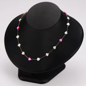 Close-up detail of a colorful dopamine style shell heart necklace on a black jewelry bust