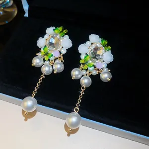 Makroaufnahme von Vintage-Palast-Ohrringen mit Kristallblumen, Schmetterlingen und Perlen.