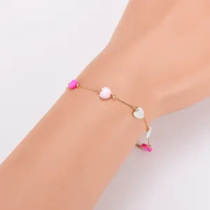 Macro view of a gold chain bracelet with colorful heart-shaped shell beads on a wrist