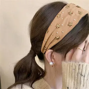 Close-up view of vintage brown fabric headband decorated with gold stars and white pearls