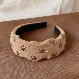 Close-up of bronze star studs on a retro tan wide fabric headband with wave edges.