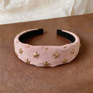 Close-up of a pink padded headband with gold star studs and a high skull top design