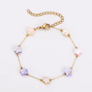 Detail of a stainless steel gold bracelet with colorful pastel shell flower charms