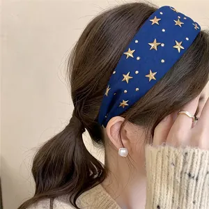 Elegant navy blue fabric headband featuring decorative gold star studs on a model