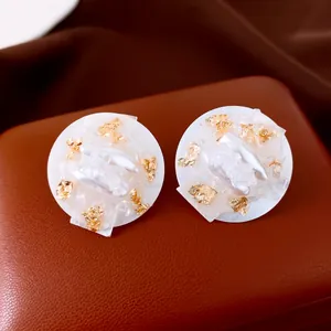 Elegant round earrings with white pearl fragments and gold leaf accents on leather base