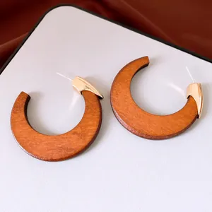 Close-up of retro wooden C-shaped stud earrings with gold metal accents