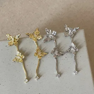 Nahaufnahme eleganter Schmetterling-Ohrringe mit Quasten und funkelnden Strasssteinen.