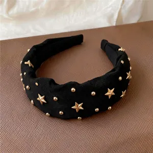 Close-up view of vintage black fabric headband featuring gold star and stud embellishments