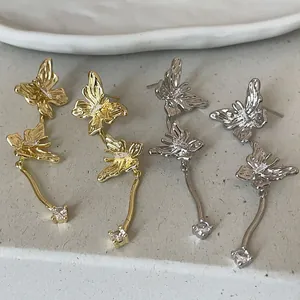 Nahaufnahme von eleganten Schmetterling-Ohrringen mit Quasten in Gold und Silber