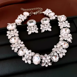 Close-up view of a sparkling oval rhinestone and flower necklace with matching earrings set