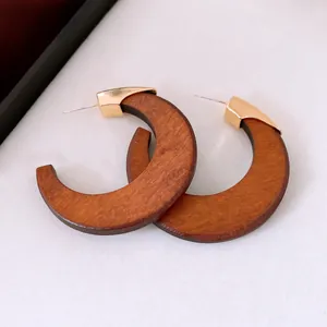 Detailed macro shot of vintage wooden C-shaped hoop earrings with gold metal accents.