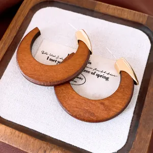 Close-up detail of vintage wooden C-shaped stud earrings with gold metal accents