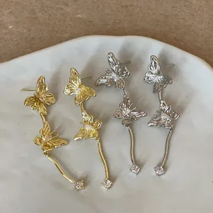 Detailansicht eleganter Schmetterling-Ohrringe in Gold und Silber mit Strasssteinen.