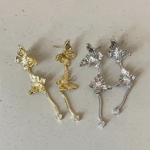 Detailaufnahme von Schmetterling-Quasten-Ohrringen in Gold und Silber mit Glitzersteinen