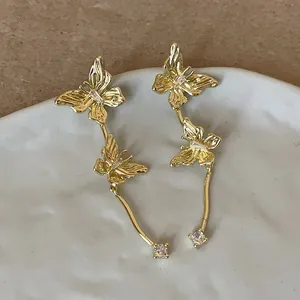 Detailansicht eleganter goldfarbener Doppel-Schmetterlingsohrringe mit Kristallquasten