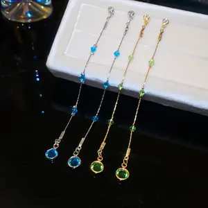 Detail view of elegant long tassel earrings with sparkling blue and green crystals