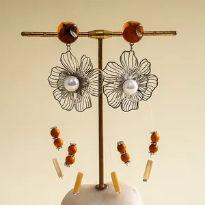 Nahaufnahme von Vintage-Ohrringen mit Metallblumen, Harzperlen und Quasten.