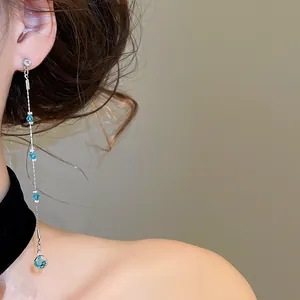 Detailed view of long dangling earrings featuring sparkling blue crystals and silver chain
