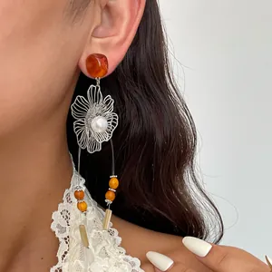 Detailansicht der Vintage-Ohrringe mit hohler Metallblume und Harzperlen am Ohr