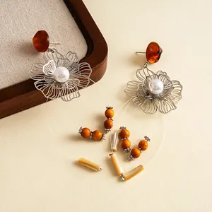 Detaillierte Nahaufnahme von Vintage-Ohrringen mit hohlen Metallblumen und Harzquasten