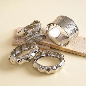 Detailopname van zilveren metalen armbanden met blad- en golfpatronen en texturen.