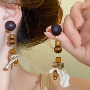 Macro detail shot showing the textures of wooden beads and shell pendants on ethnic earrings