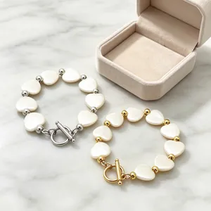 Nahaufnahme von Herz-Muschel-Perlenarmbändern mit OT-Verschluss in Gold und Silber