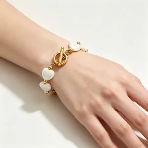 Elegantes Herzmuschelperlenarmband mit goldenem OT-Knebelverschluss am Handgelenk