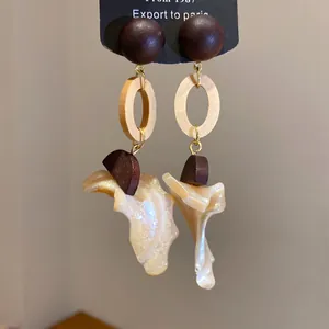 Detailed view of retro ethnic wood and shell drop earrings with silver needles