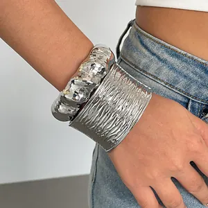 Detailweergave van een getextureerde zilveren metalen manchet en dikke armband
