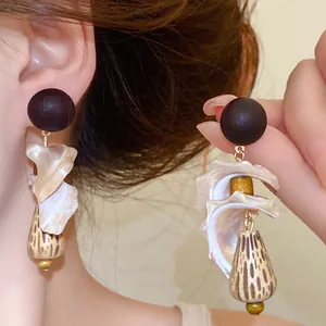 Detailed view of retro shell and wood drop earrings showing natural luster and textures