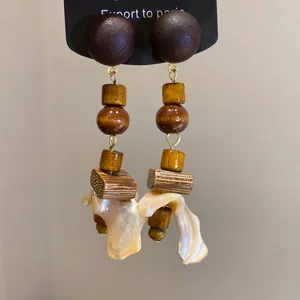 Detail view of ethnic wood and shell drop earrings with glossy finish and textures