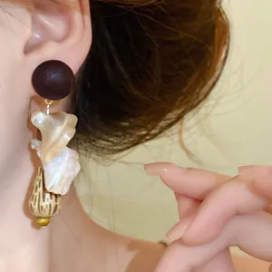 Detail of vintage ethnic earrings featuring wooden studs and iridescent shell drops