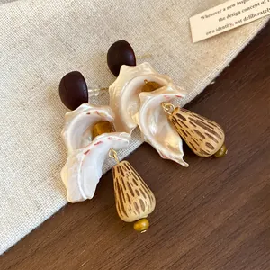 Close-up of retro ethnic style earrings with natural wood drops and pearlescent shell accents.