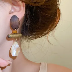 Close-up detail of retro wooden and pearlescent shell teardrop earrings on model