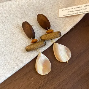 Close-up detail of retro wood and shell teardrop earrings displayed on a linen background