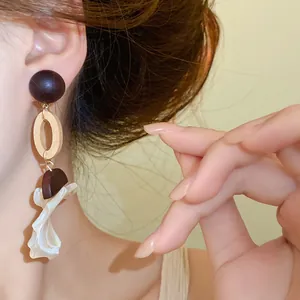 Detailed view of vintage wood and shell pendant drop earrings worn by an elegant model