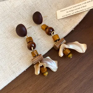 Detailed close-up of vintage earrings featuring wood beads and irregular shell pendants.