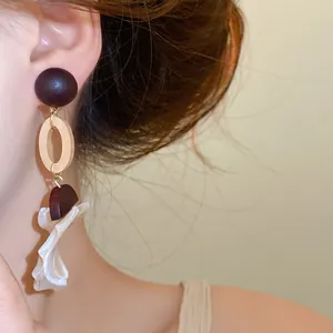 Close-up of retro wood and shell pendant earrings worn by a model for detail view.
