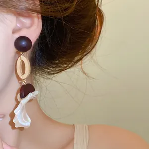 Macro detail of vintage wood shell drop earrings on a model's ear, ethnic chic style