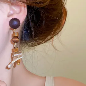 Macro detail of retro ethnic drop earrings featuring natural wood beads and shell accents