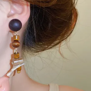 Close-up of retro ethnic drop earrings featuring wood beads and shell piece