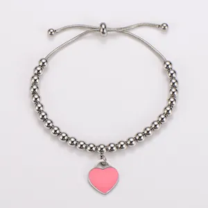 Nahaufnahme eines Armbands aus Edelstahlperlen mit einem rosa Emaille-Herz-Anhänger