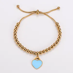 Detailansicht eines goldenen Perlenarmbands mit hellblauem Herzanhänger
